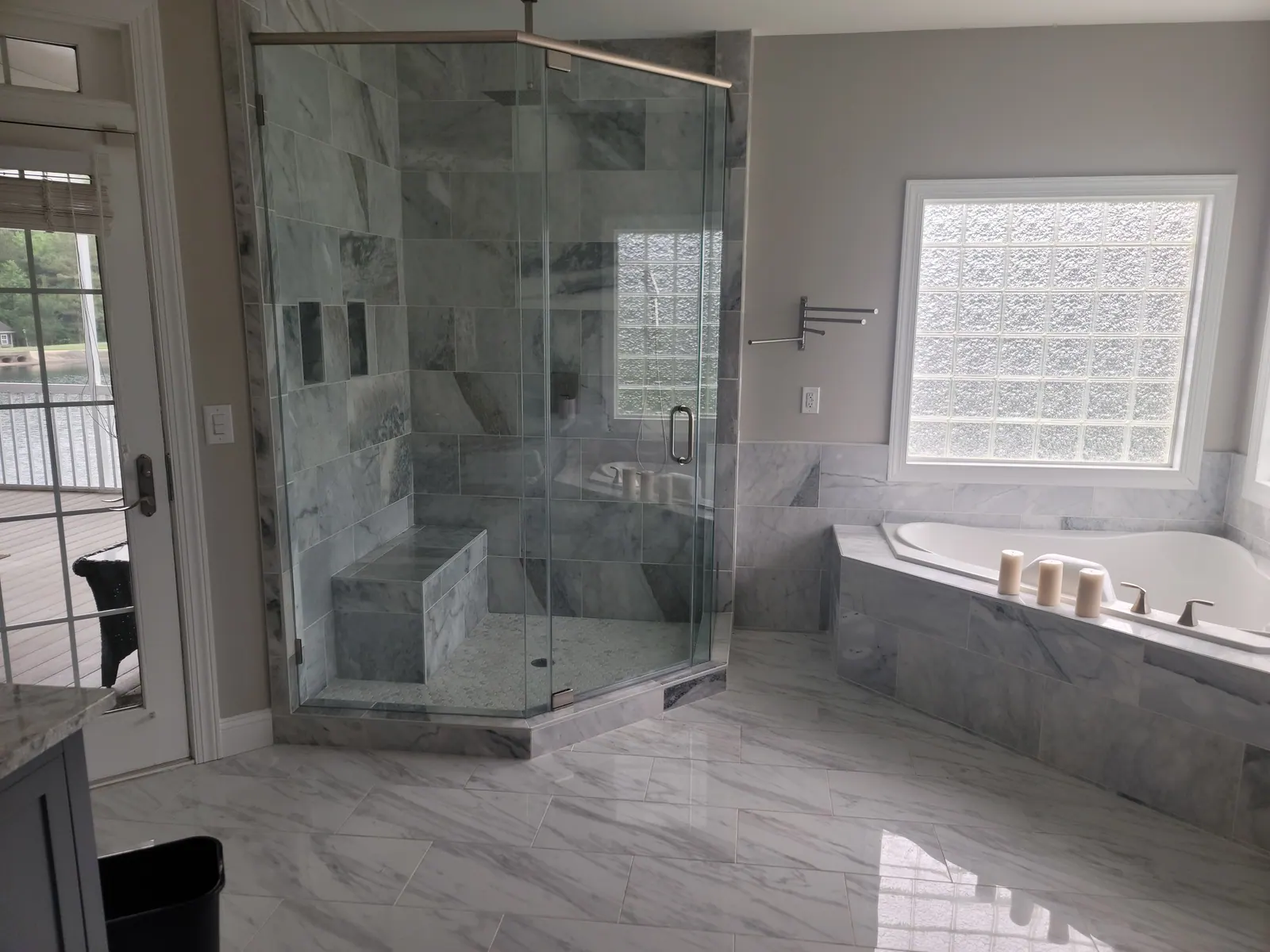 Remodeled bathroom with a frameless glass shower, tiled soaking tub and marble-look floor