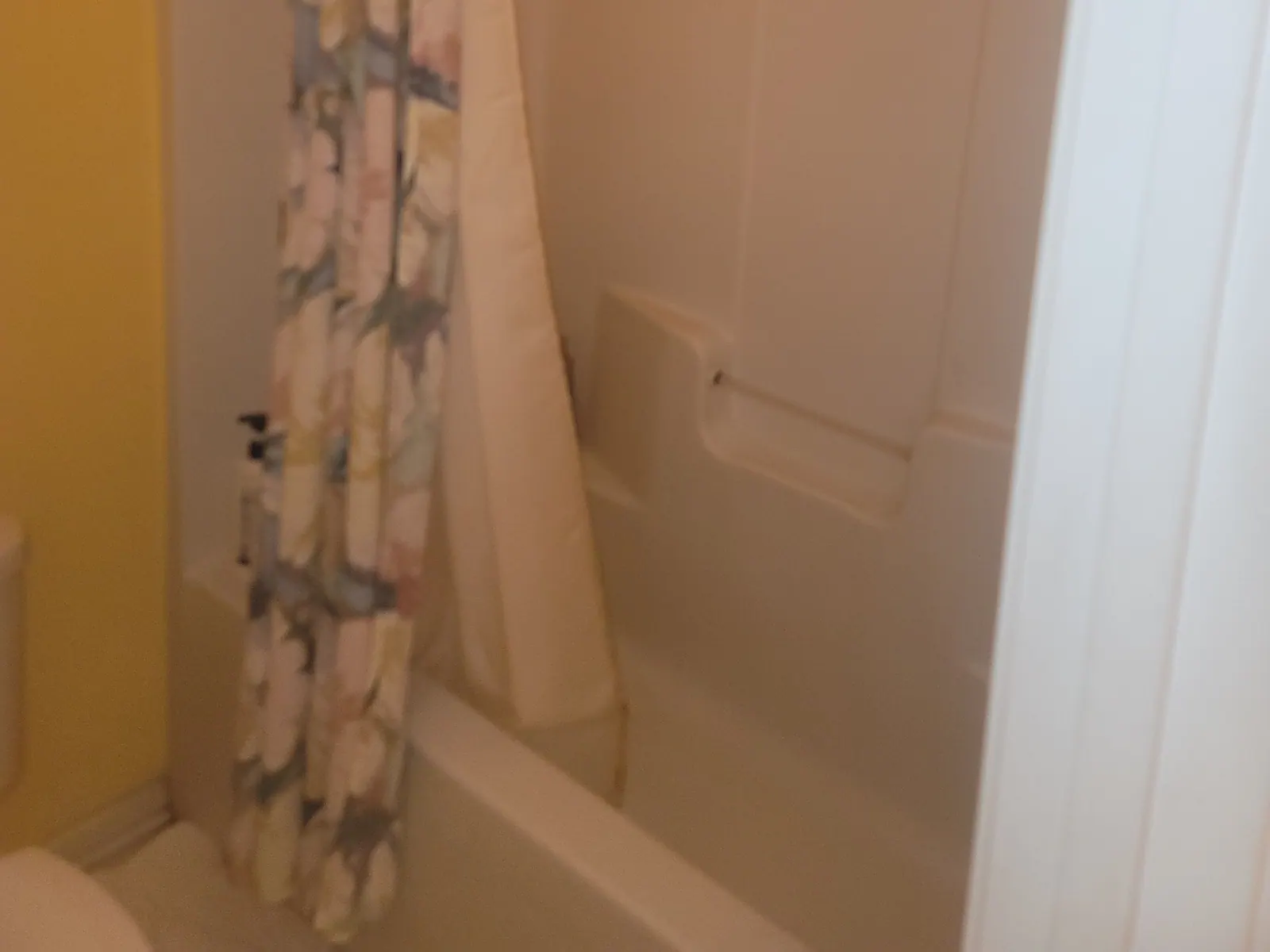 Older bathtub and surround with a shower curtain before replacement