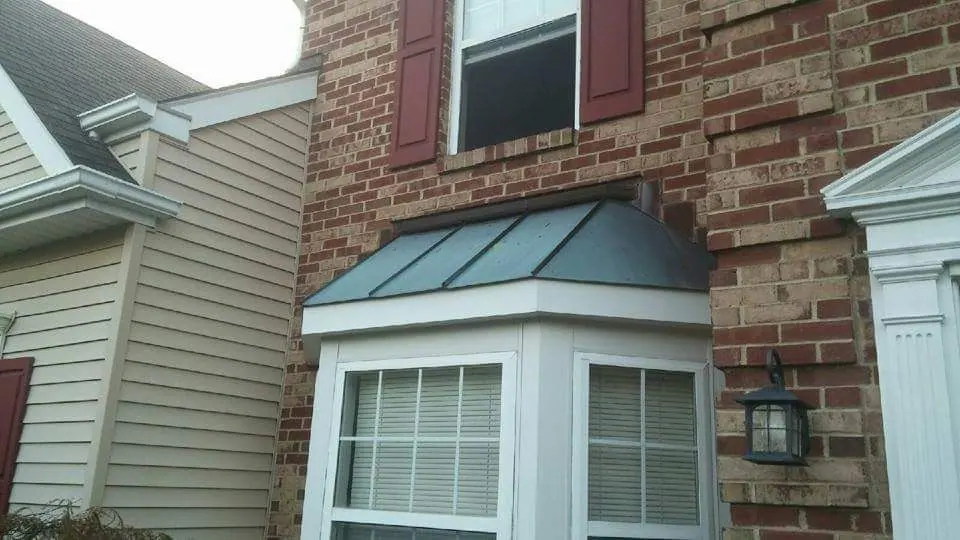 Metal roof installed over a bay window on a brick home
