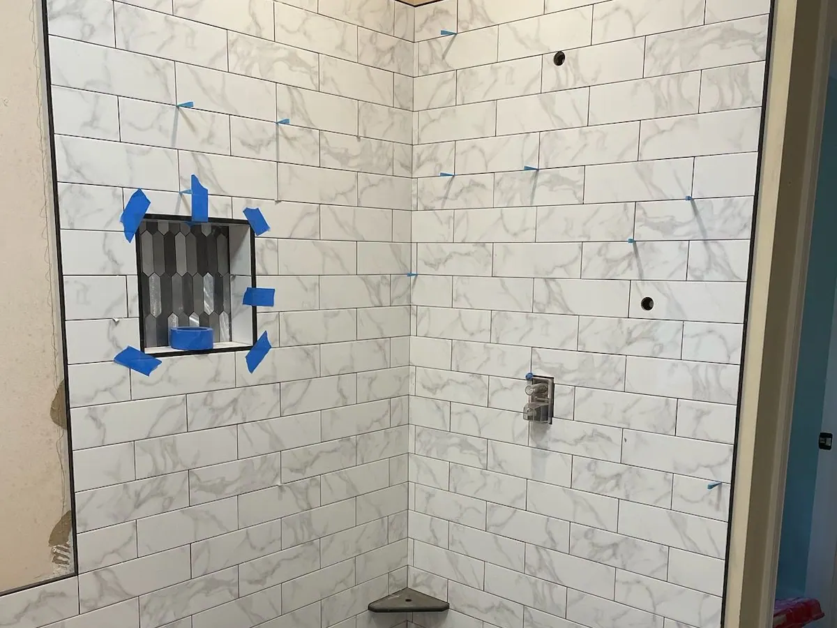 Marble-look subway tile and a niche going into a new shower
