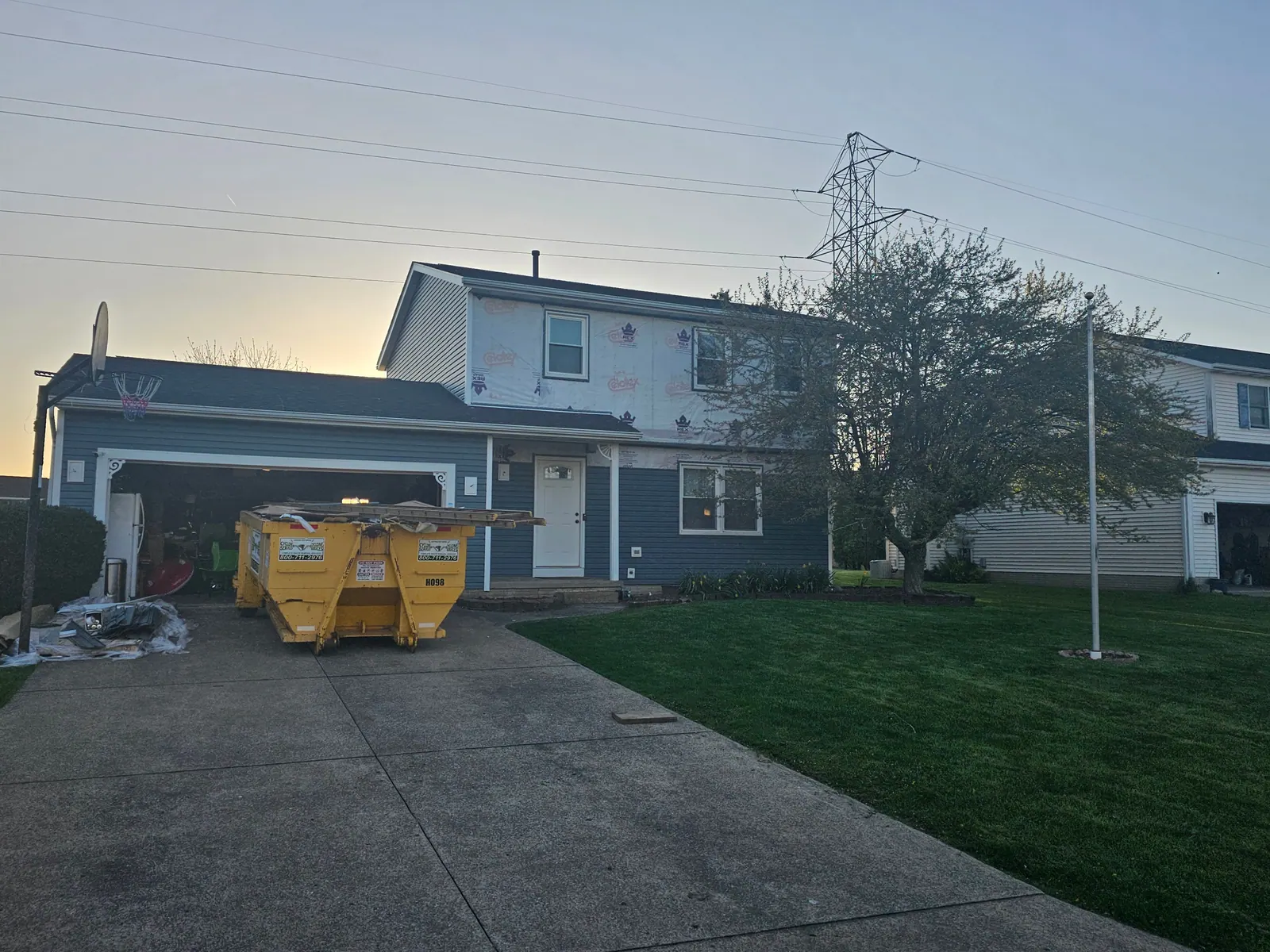 Siding replacement in progress with house wrap on the upper story